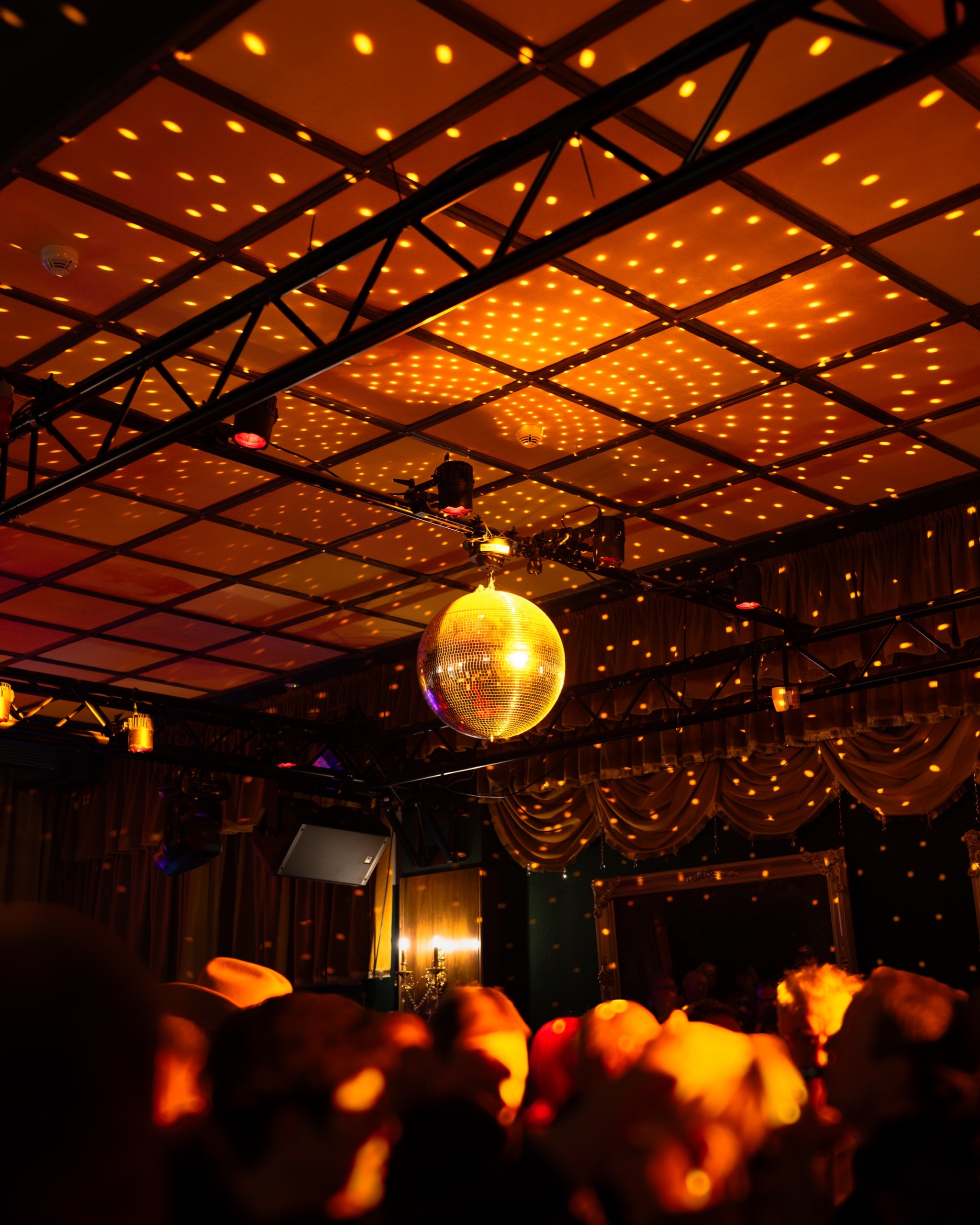 View from stage of three musicians facing a crowd holding up phone lights in a dark venue